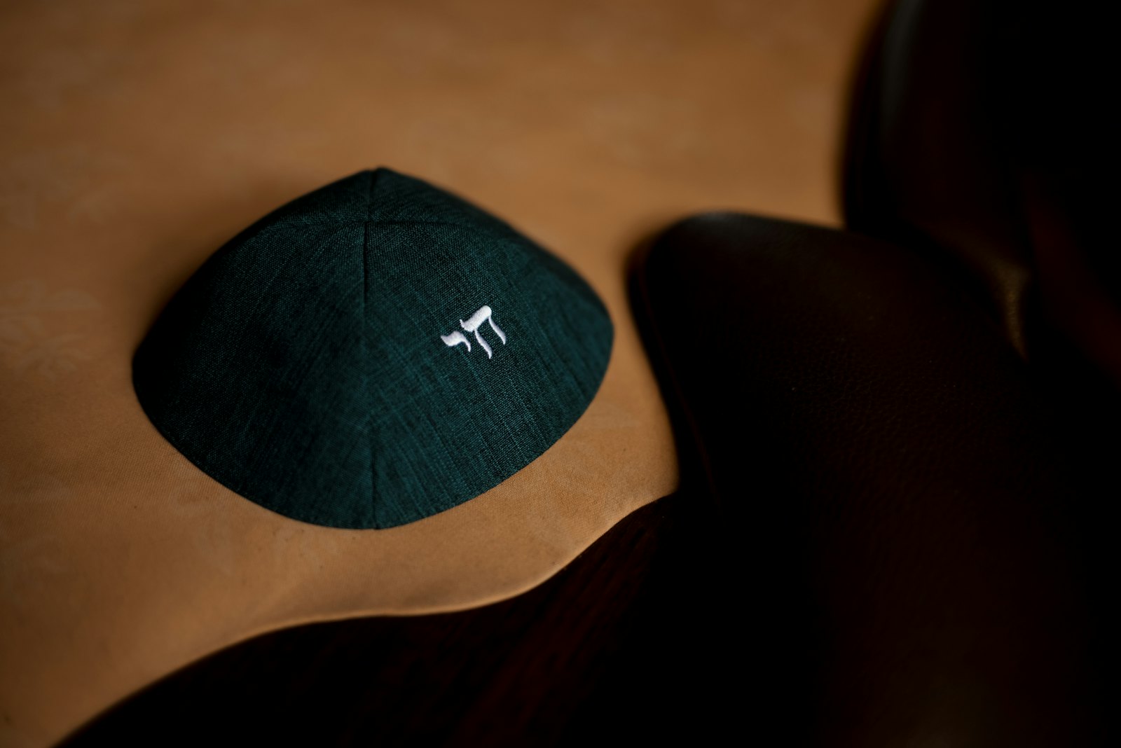 A dark green kippah embroidered with the word chai